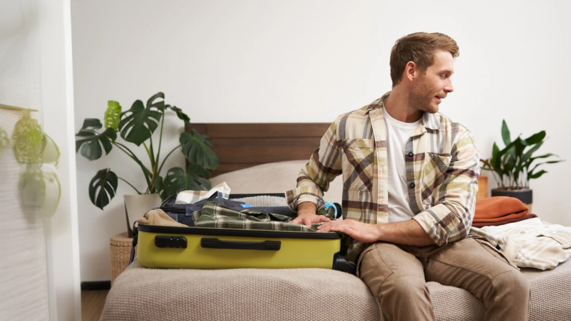 Man packing suitcase in bedroom before travel or move