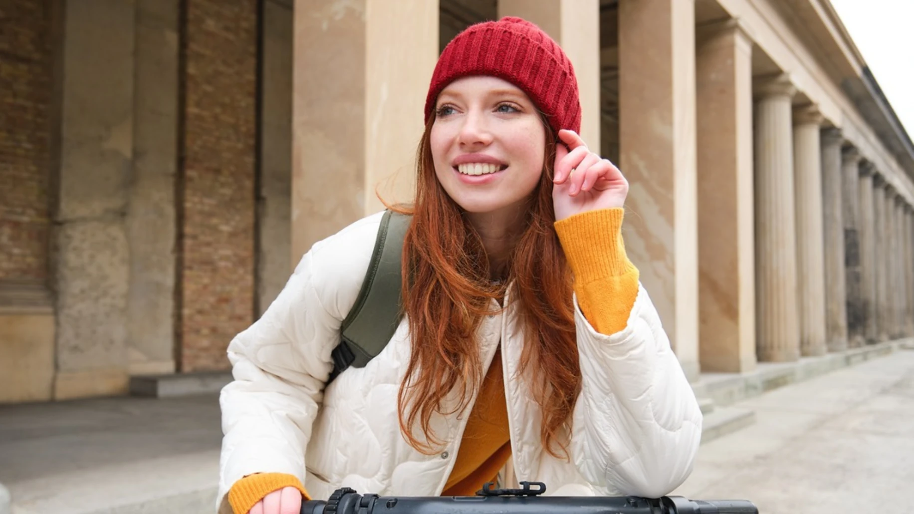 Young woman smiling while traveling with backpack in an urban setting